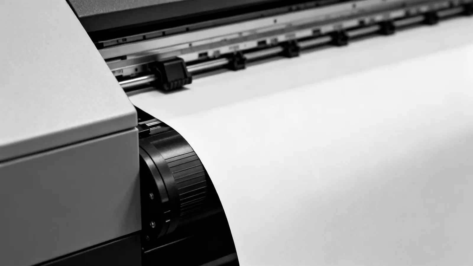Großformatdrucker beim Ausgeben eines breiten Papierbogens über die Walze
